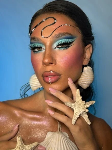 Bold turquoise eye makeup and seashell accessories by Anna Balantinou