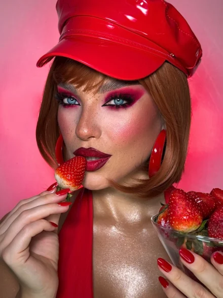 Strawberry-themed makeup look with vivid blush and red cap, by Anna Balantinou